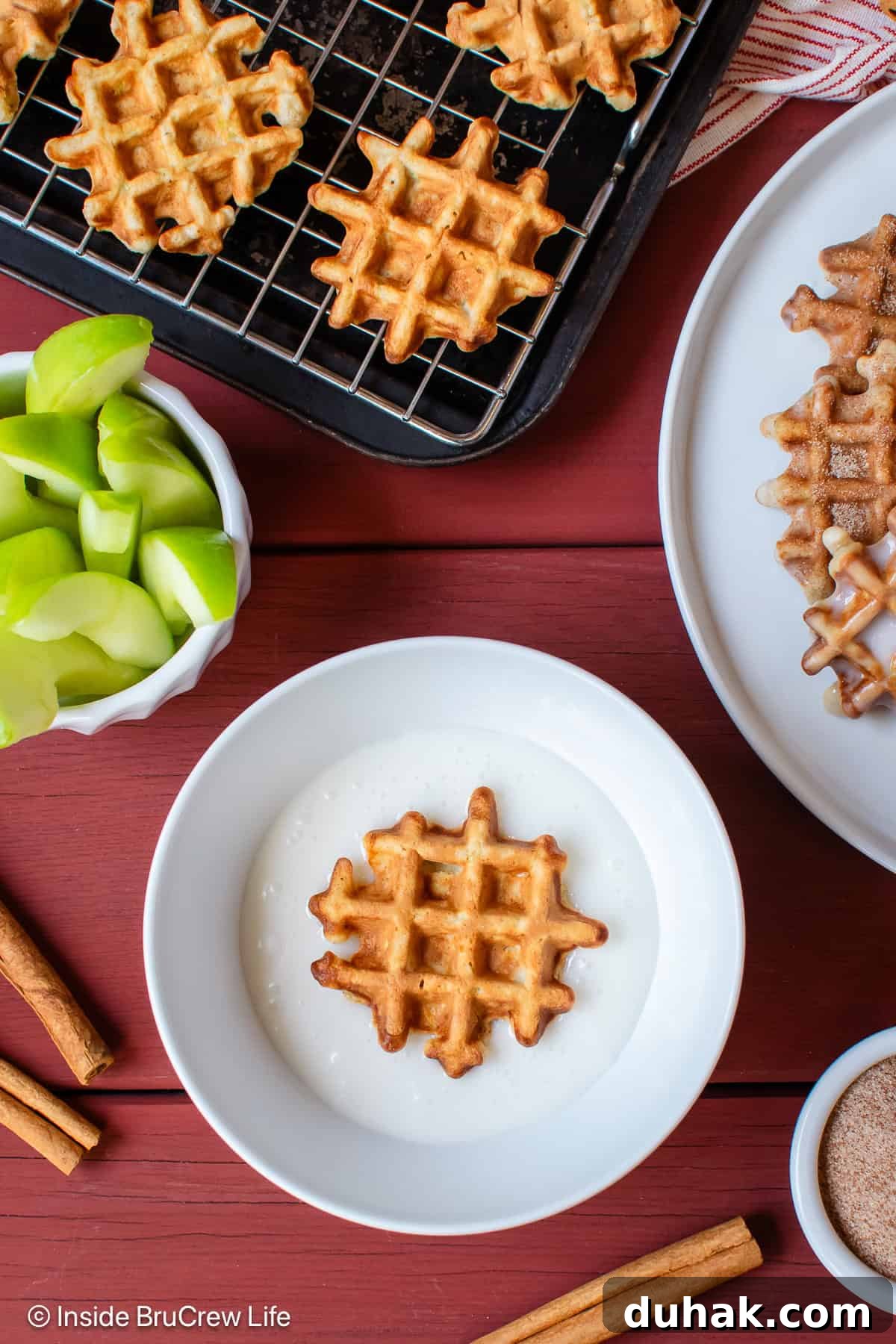 Waffle donuts being dipped into a sweet glaze.