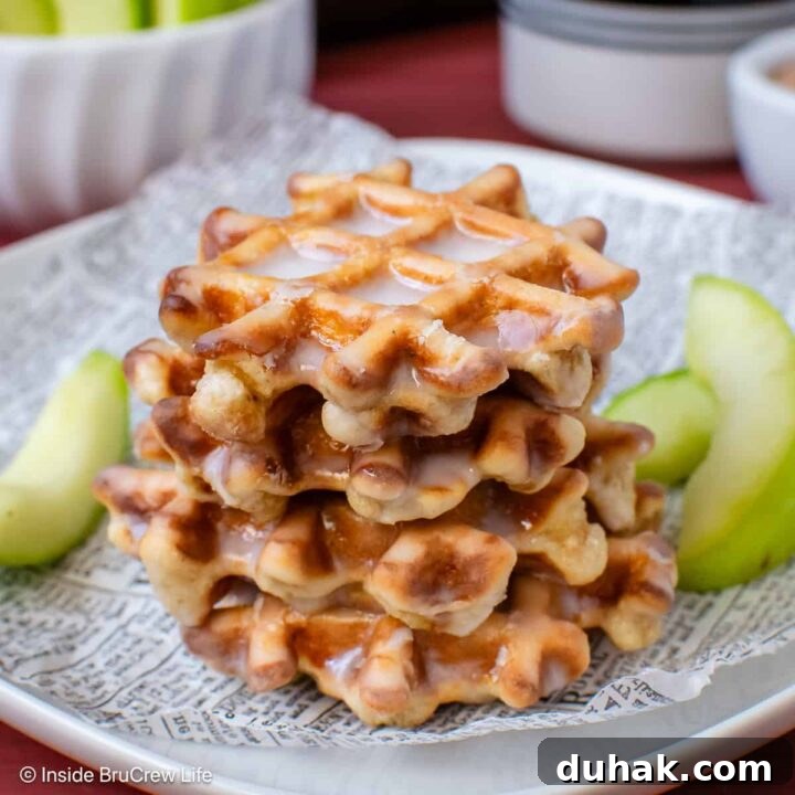 A stack of waffle donuts on a plate with apple slices.
