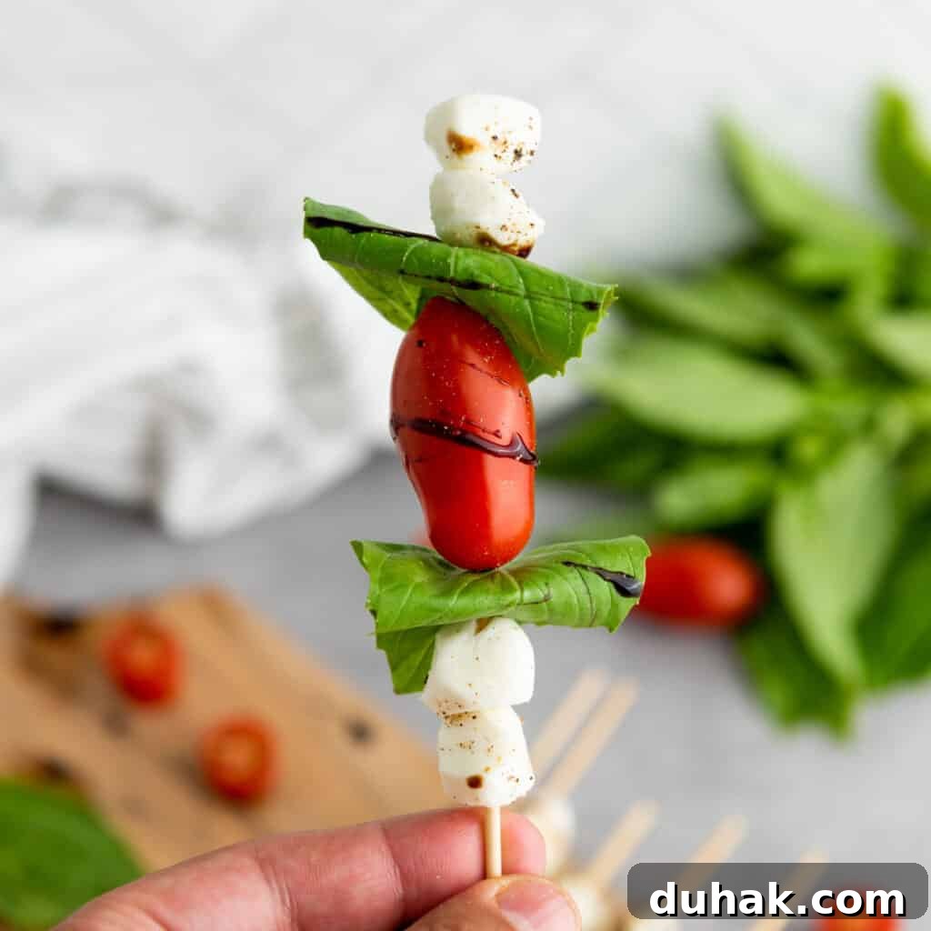 Caprese Skewers Recipe: Cherry Tomato, Mozzarella & Basil Bites 9 hand holding caprese skewer