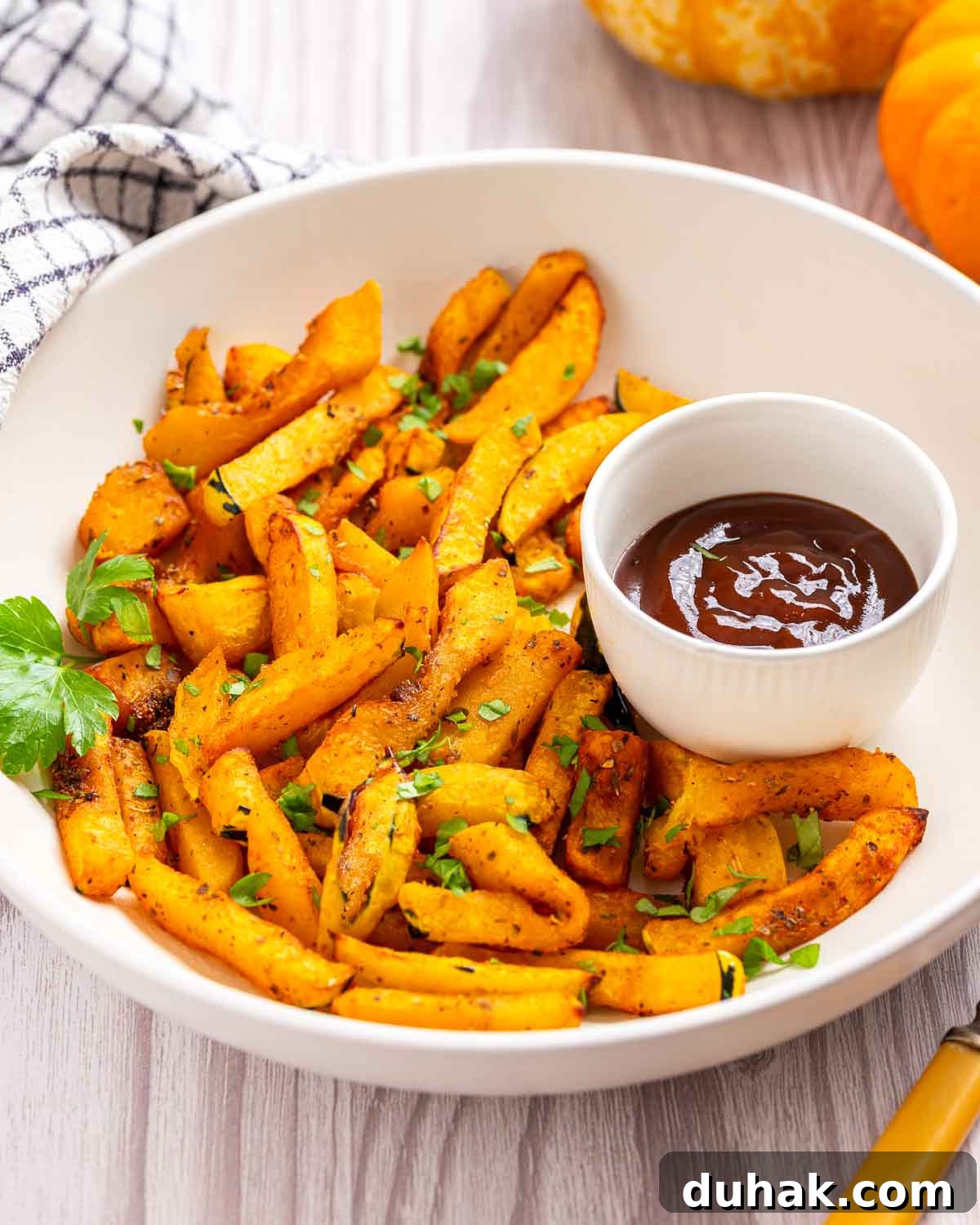 A plate of pumpkin french fries with a bowl of ketchup for dipping