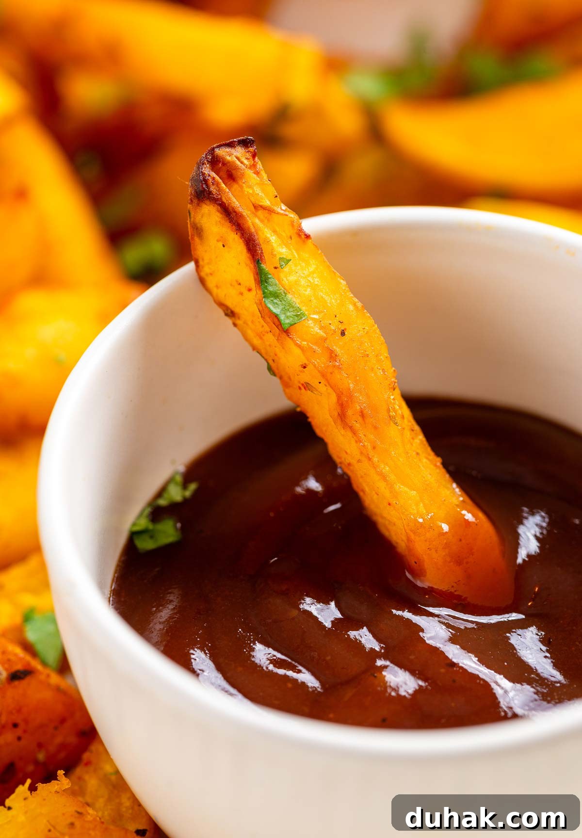 One pumpkin french fry dipped into a bowl of ketchup.