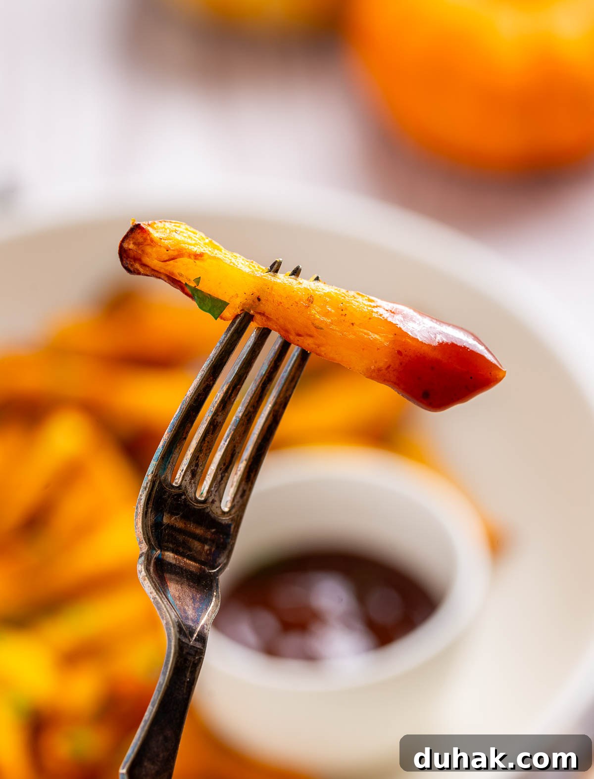 One pumpkin french fry dipped into a bowl of ketchup.