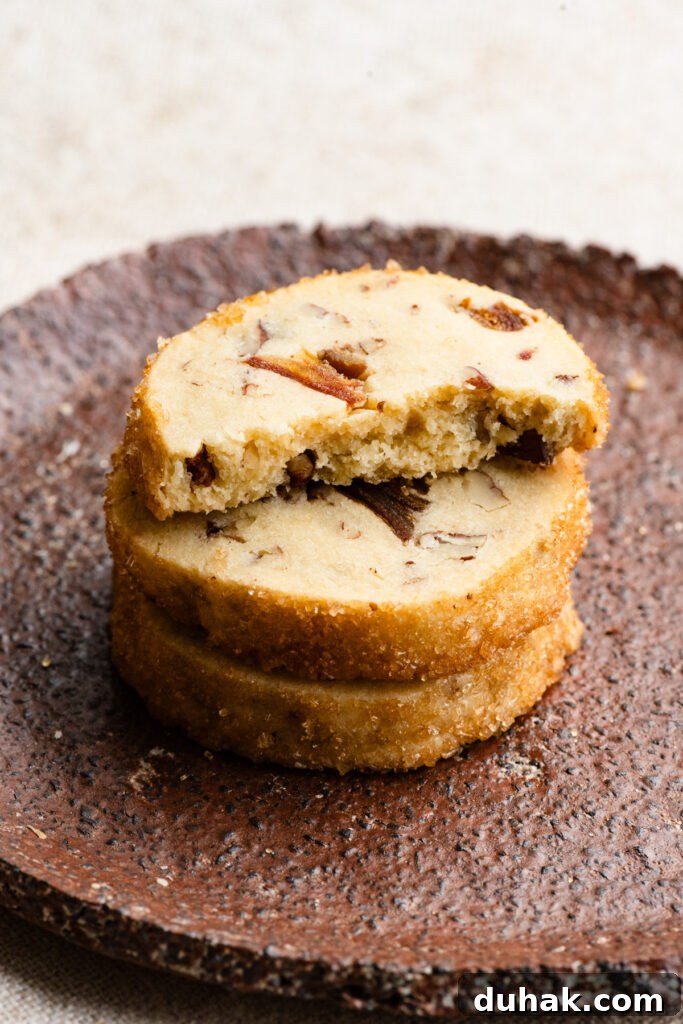 Stack of shortbread cookies on a plate with the top cookie broken in half.