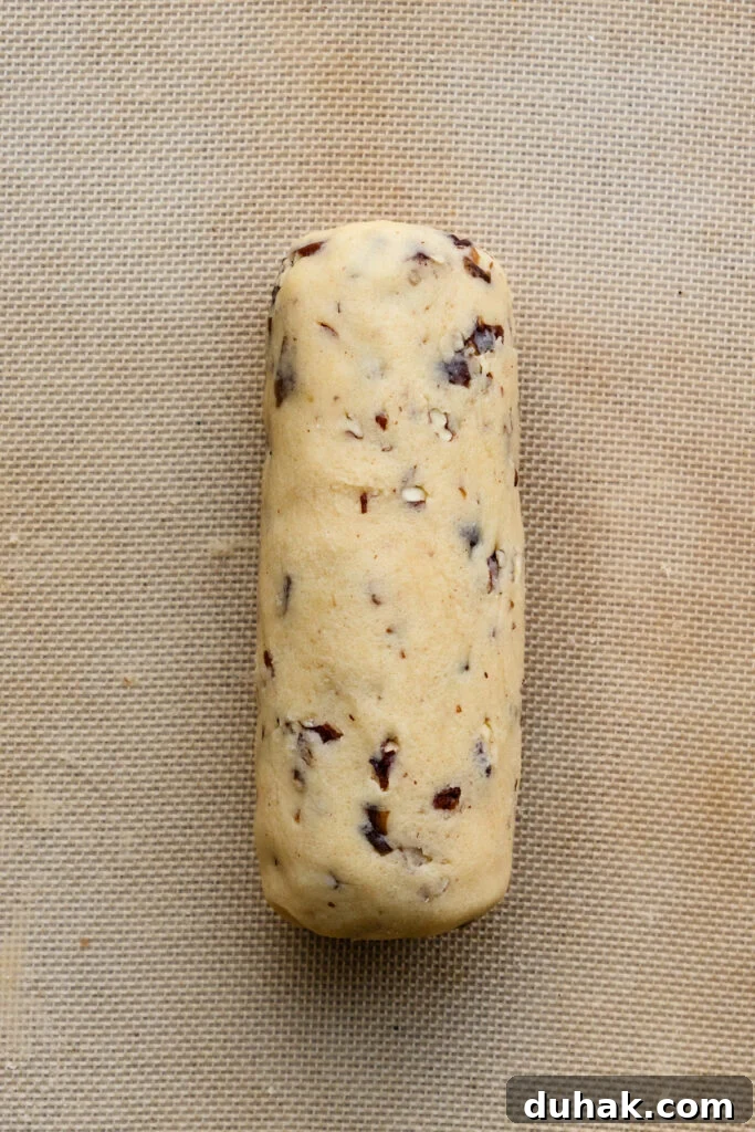 Log of unbaked shortbread cookie dough on a baking mat.