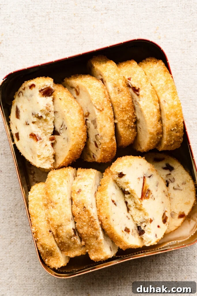 Overhead of pecan shortbread cookies with sugar crust packed in a cookie tin.