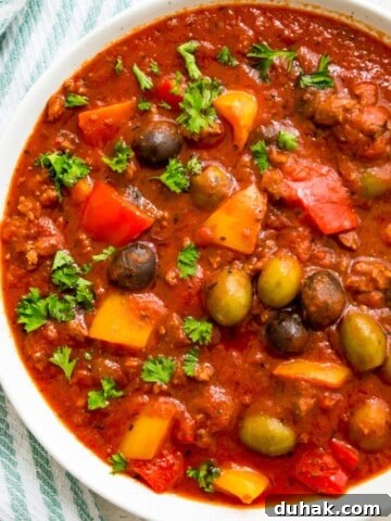 A bowl of healthy meat sauce garnished with fresh parsley.
