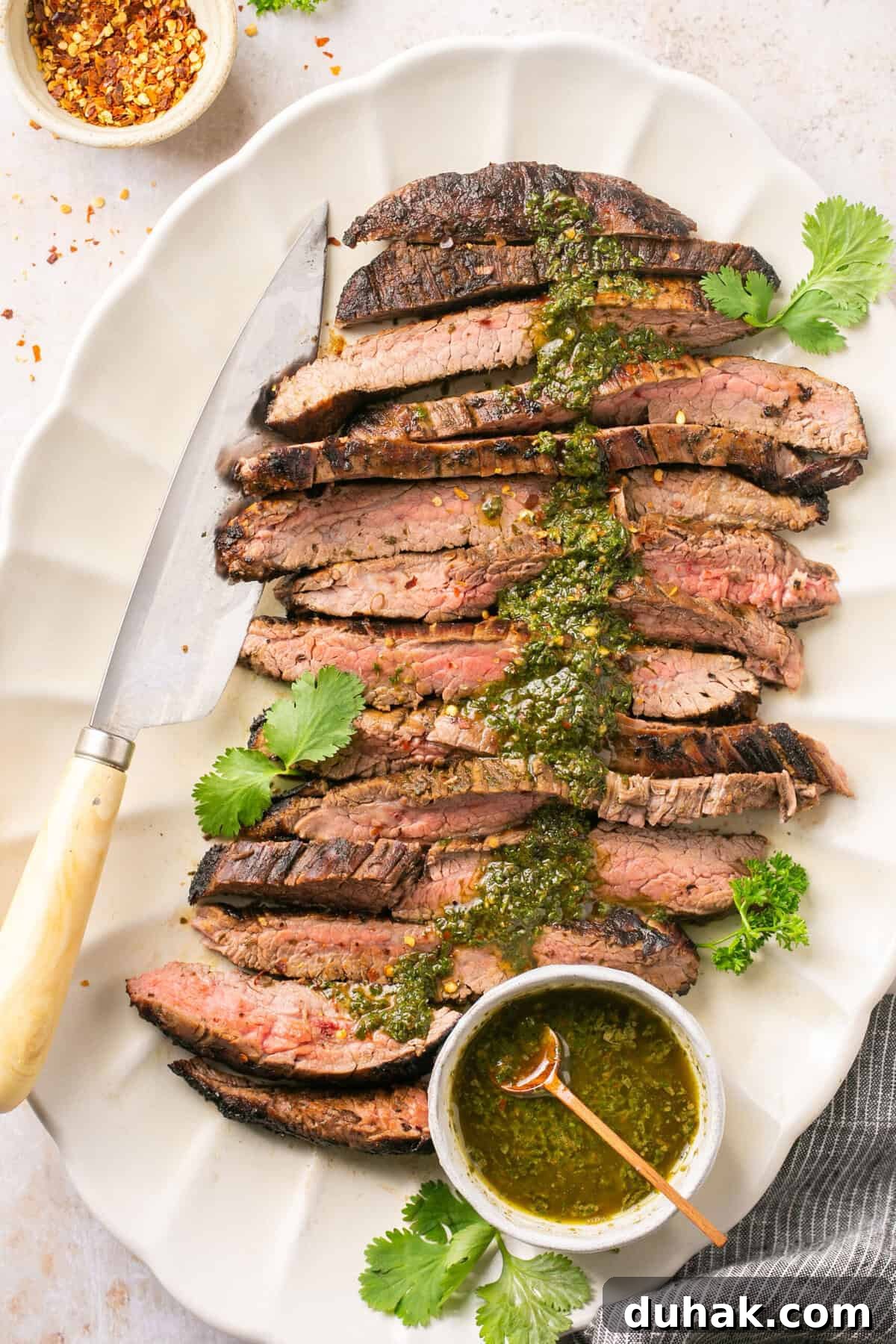 A steak cut into pieces topped with a chimichurri sauce.