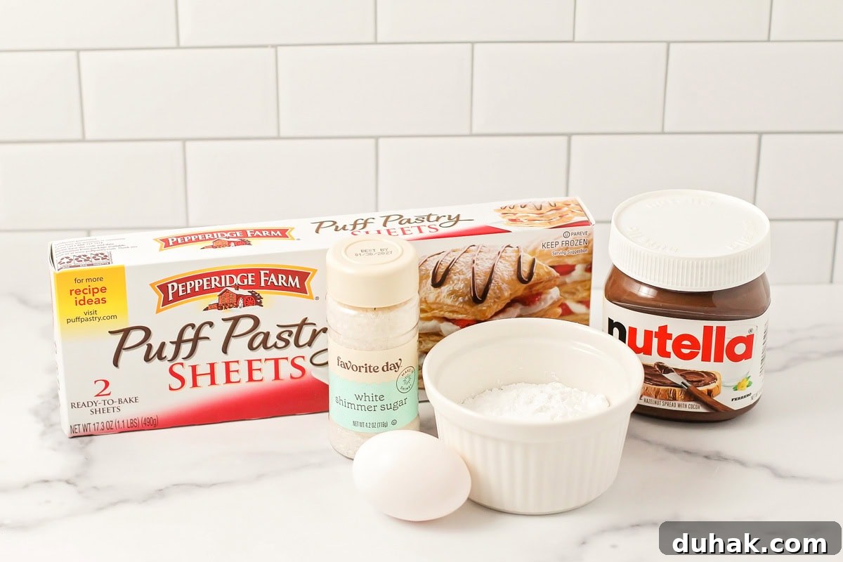 Puff pastry, Nutella, powdered sugar, and egg on a kitchen counter.