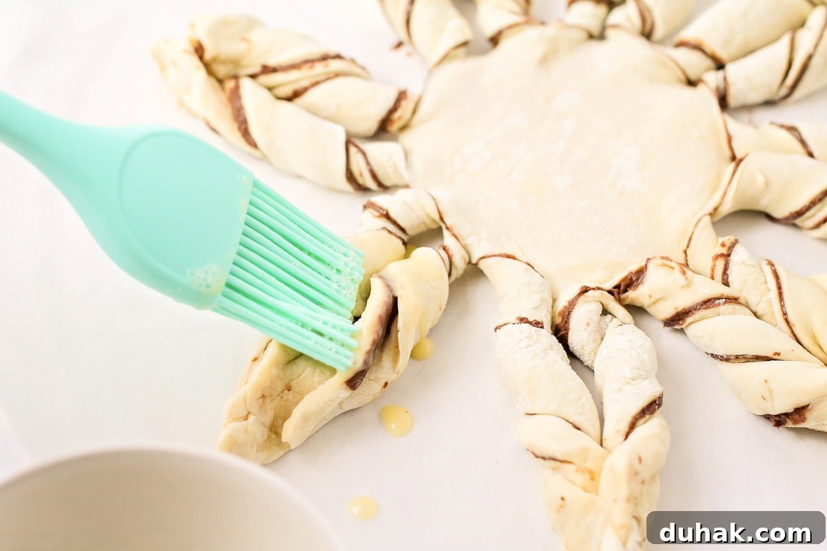 Adding egg wash to the puff pastry snowflake.
