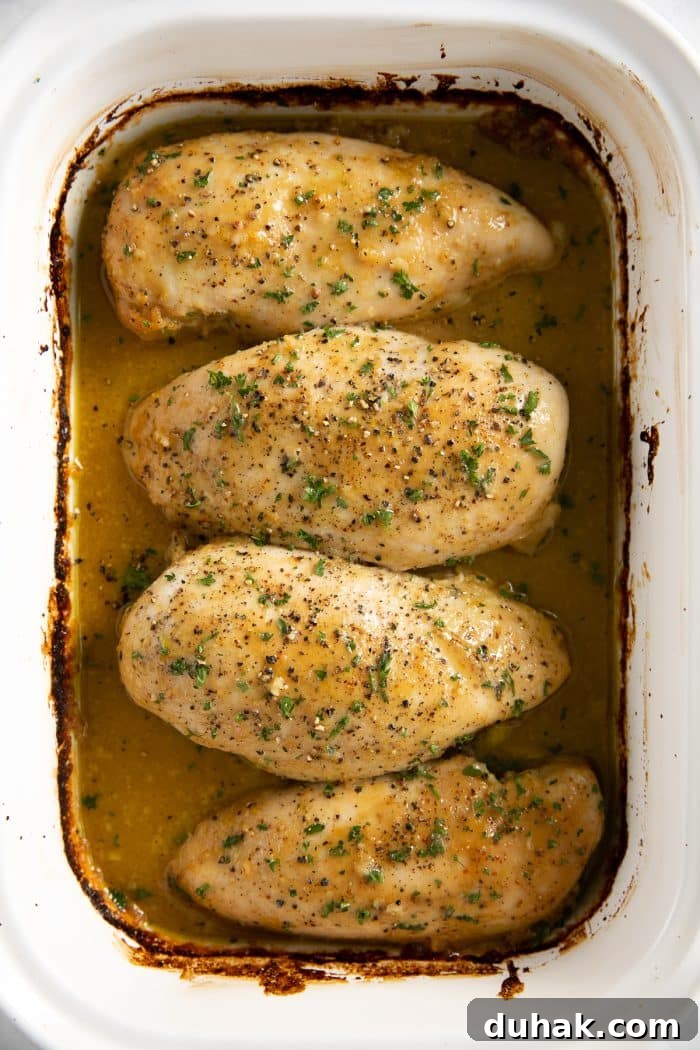 White baking dish filled with four baked chicken breasts covered with homemade honey mustard sauce.
