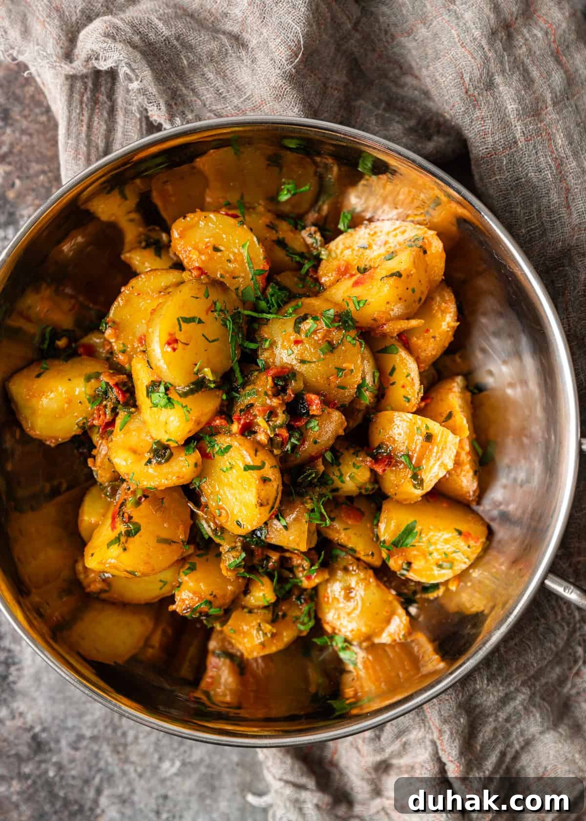 Spicy Calabrian Potatoes with Garlic and Chili Peppers 6 overhead: a metal bowl full of calabrian chili potatoes with herb butter