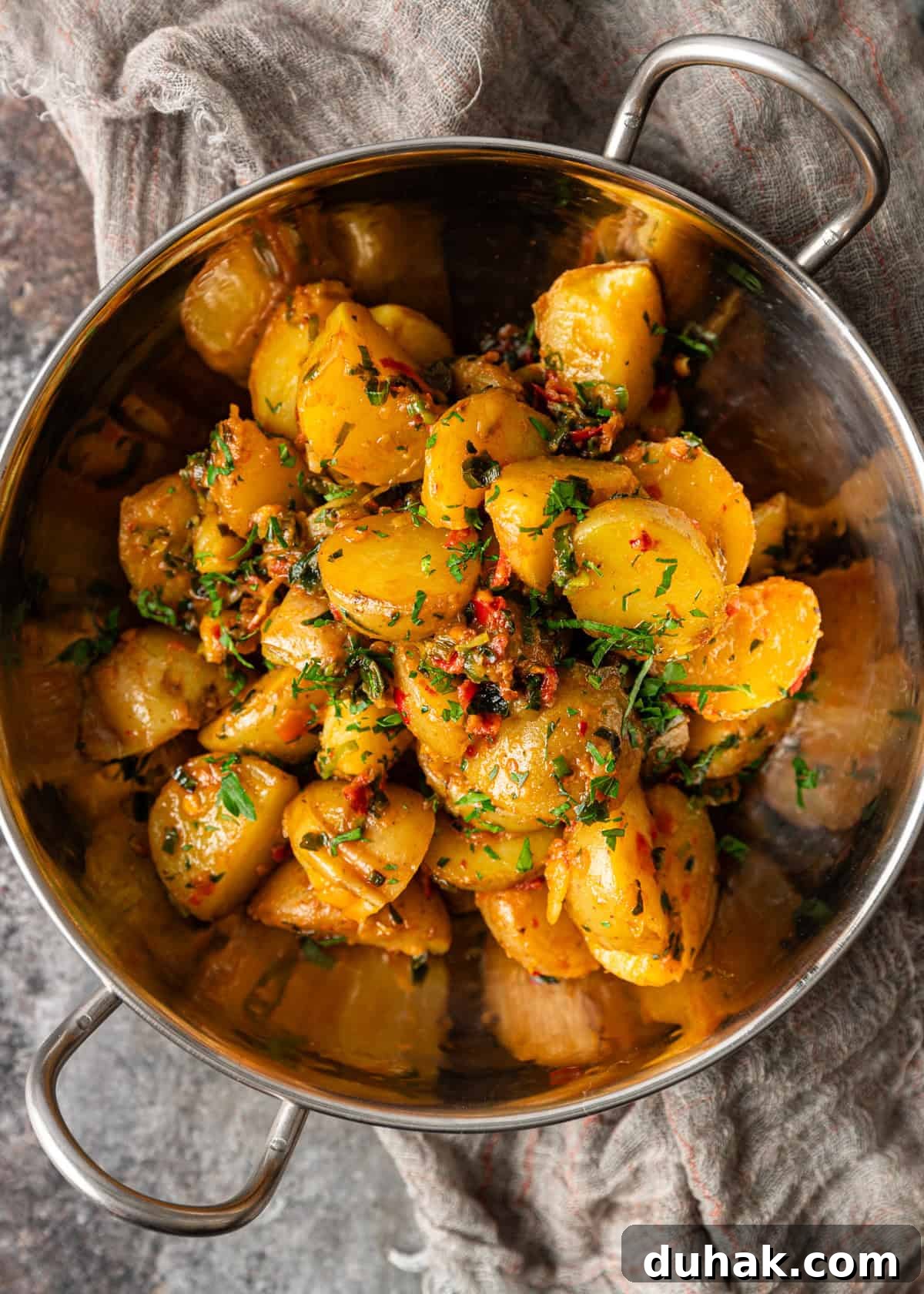 Spicy Calabrian Potatoes with Garlic and Chili Peppers 8 overhead: potatoes and peppers cooked in herb chili butter in a metal bowl