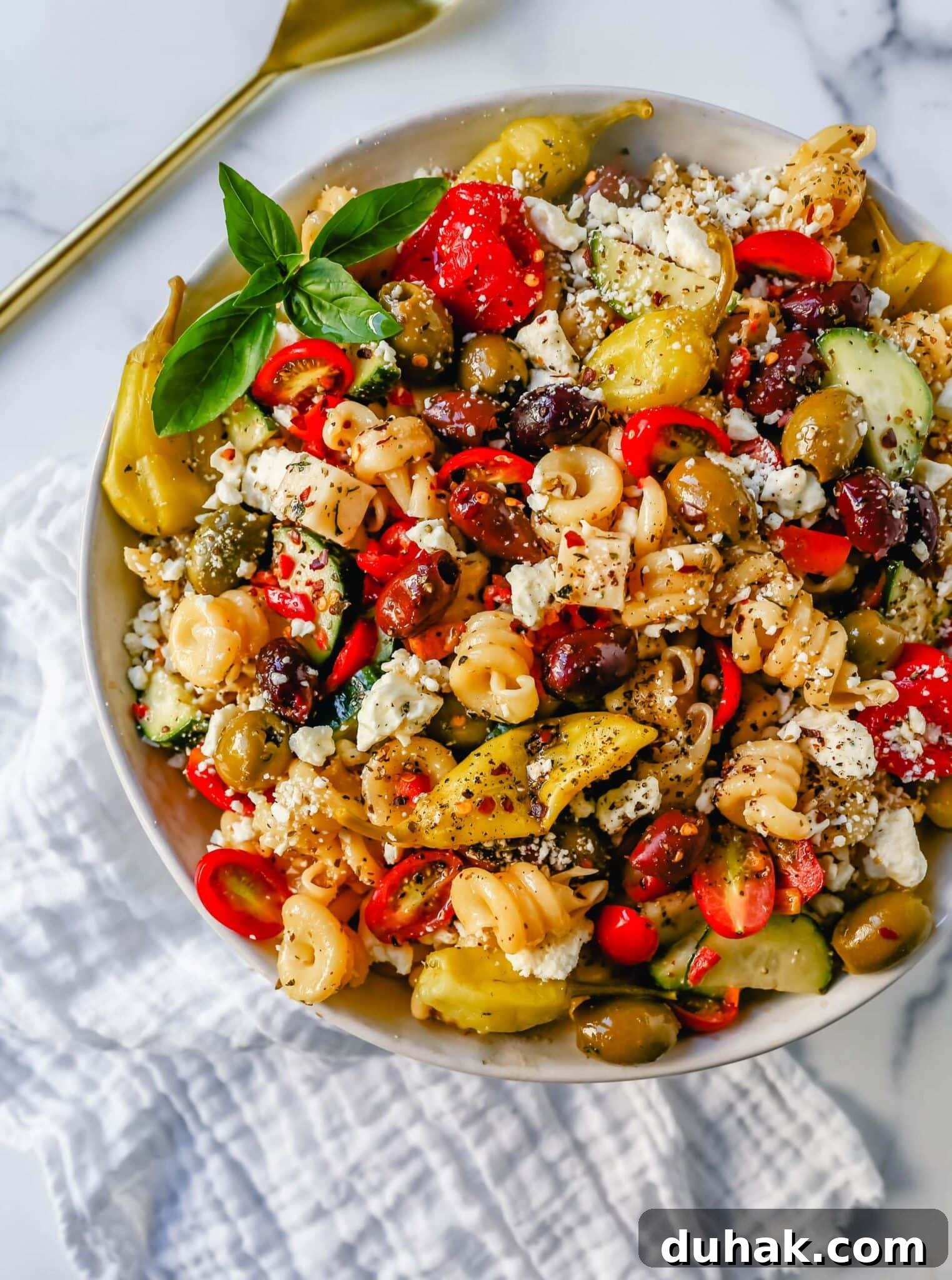 a bowl of greek pasta salad with olives and feta. 