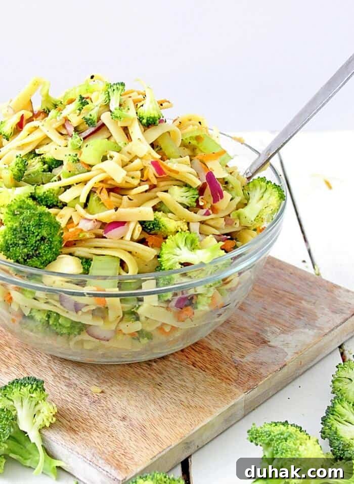 a large bowl of pasta salad with broccoli, fettucine, and apples. 