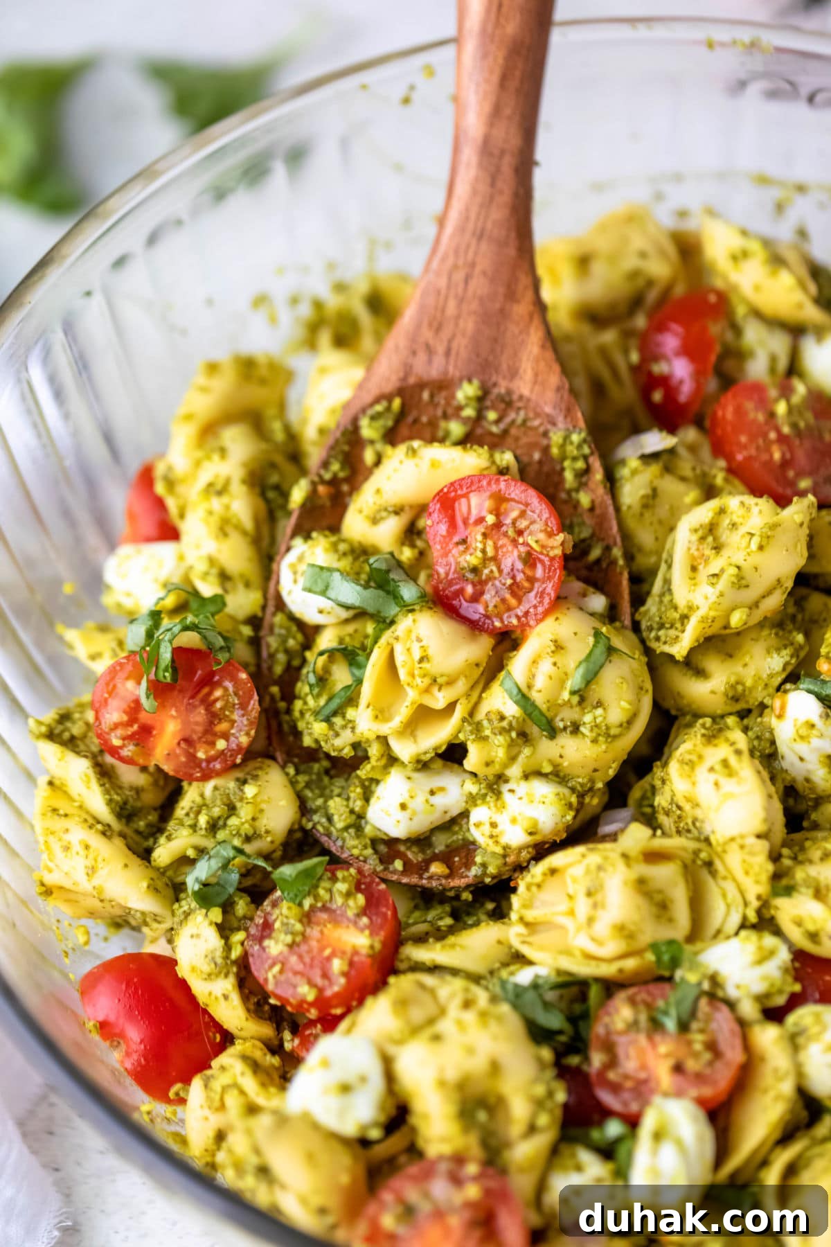 a bowl of tortellini pasta salad in pesto. 