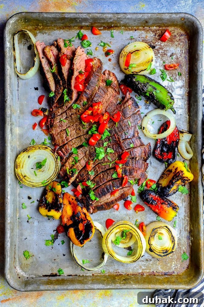 Grilled steak fajitas with onions and peppers, cooked on a baking sheet.