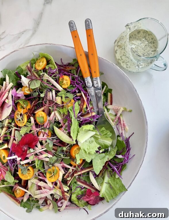 a spring salad next to a container of salad dressing 