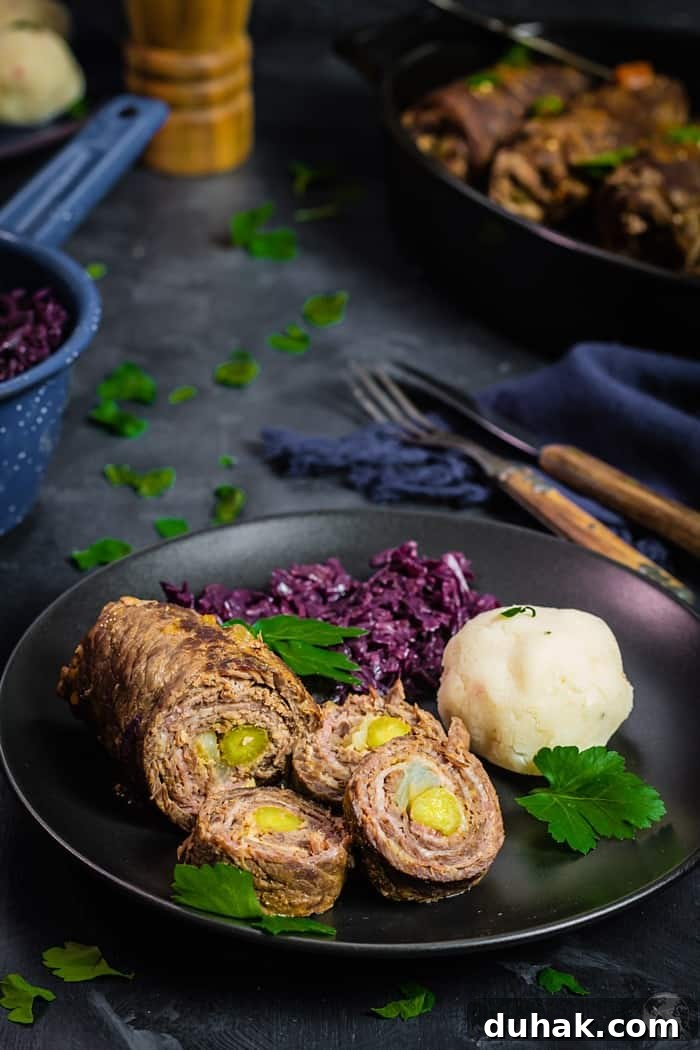 black plate on a dark blue background with rouladen, red cabbage, and dumplings.