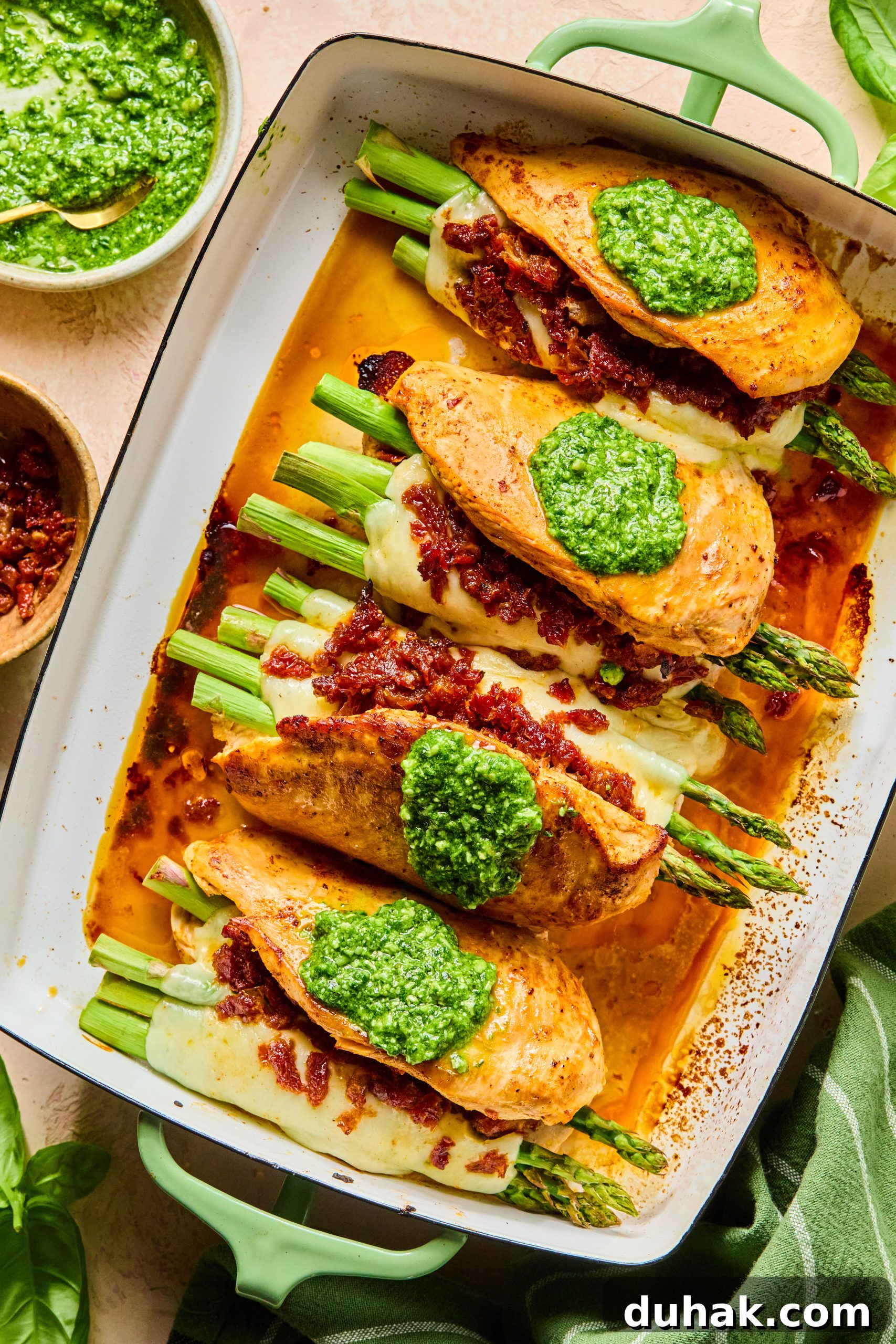 Asparagus and Sun-Dried Tomato Stuffed Chicken with Pesto and Cheese 12 A large baking dish filled with cheesy asparagus stuffed chicken breasts each topped with a spoonful of homemade pesto