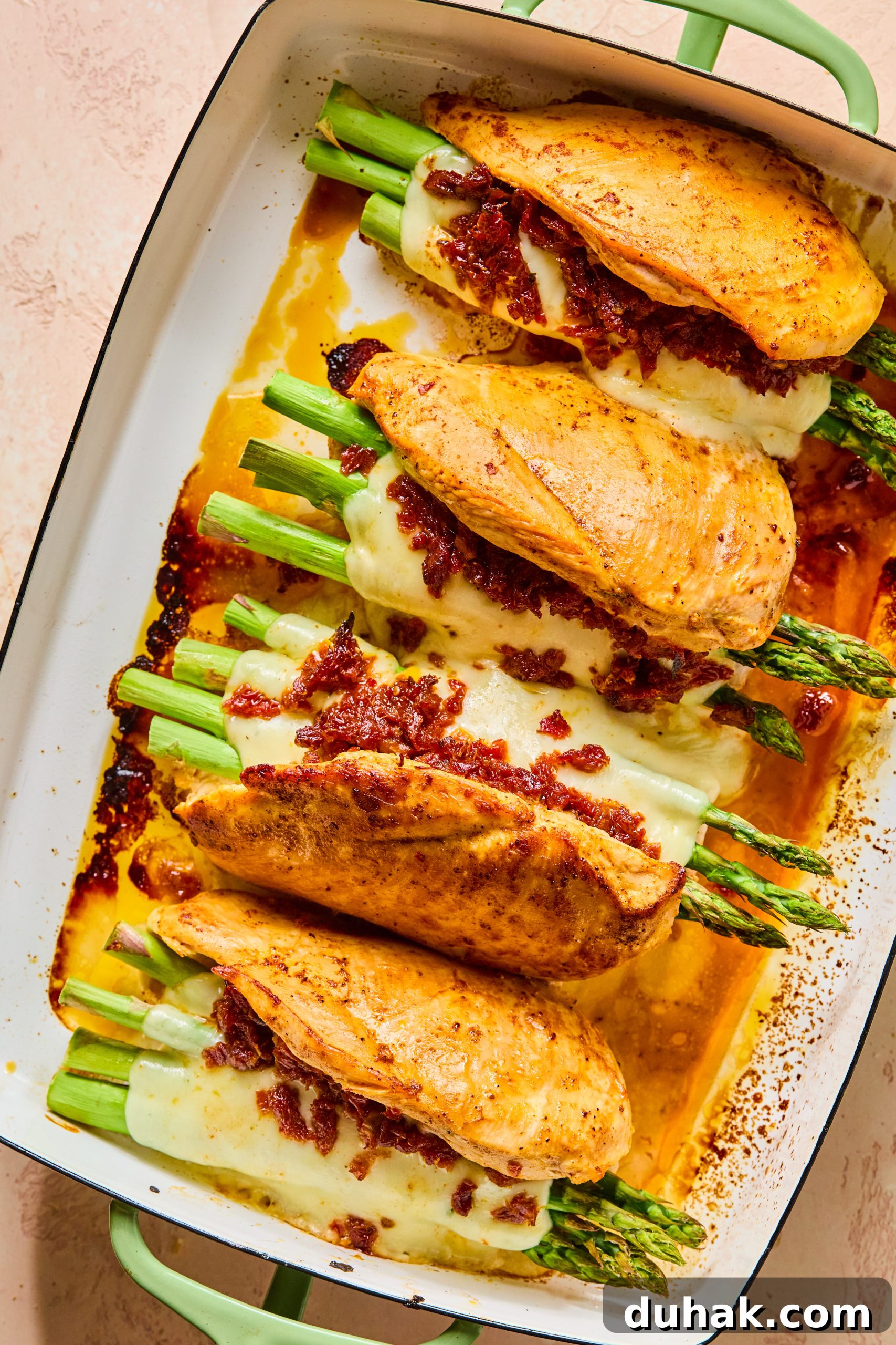 Asparagus and Sun-Dried Tomato Stuffed Chicken with Pesto and Cheese 10 Baked cheesy asparagus stuffed chicken sitting in a hot baking dish with wamr chicken juices and gooey melty mozzarella