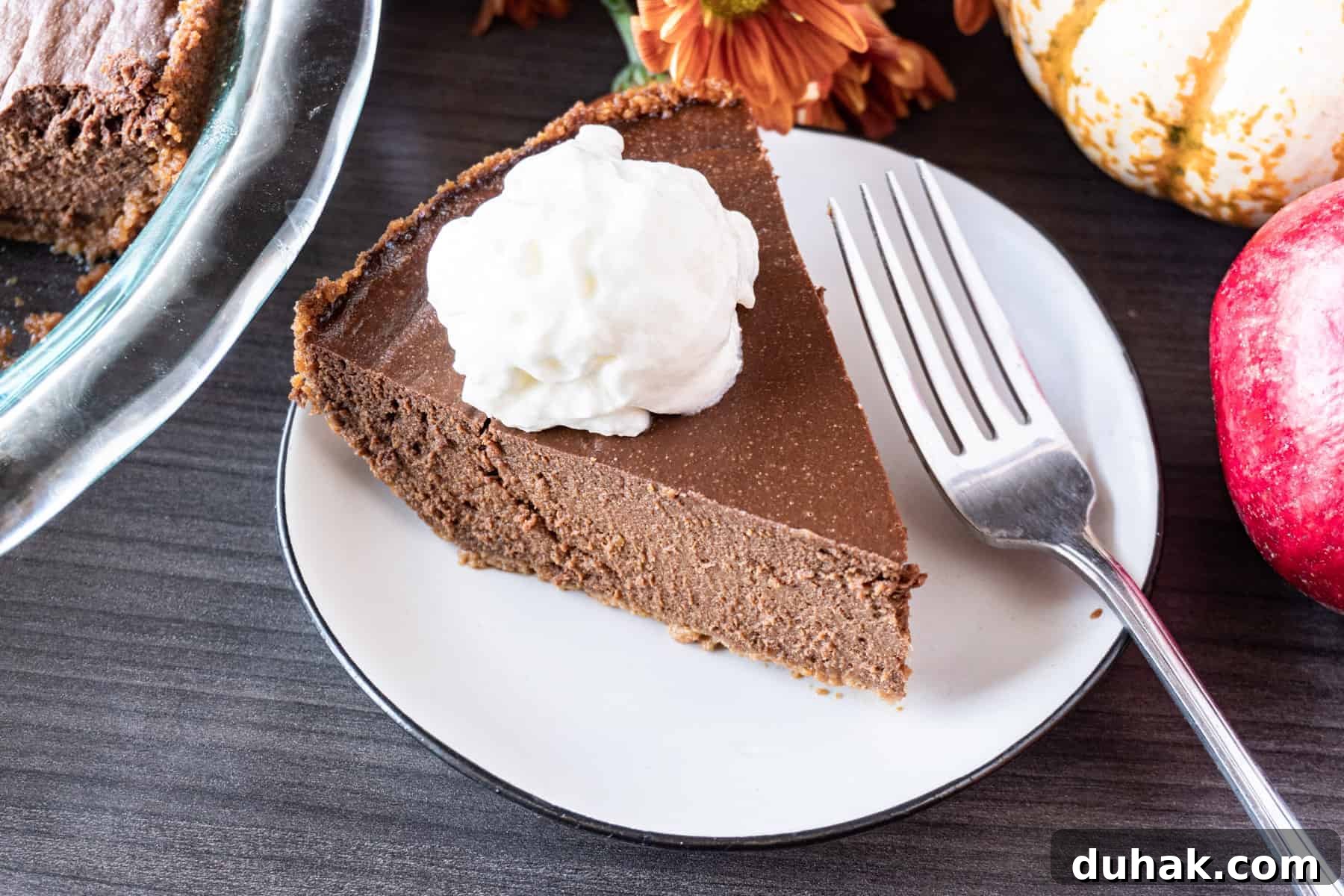 Decadent Chocolate Pumpkin Pie Recipe for Fall Desserts 14 A slice of chocolate pumpkin pie on a white plate, accompanied by a fork.