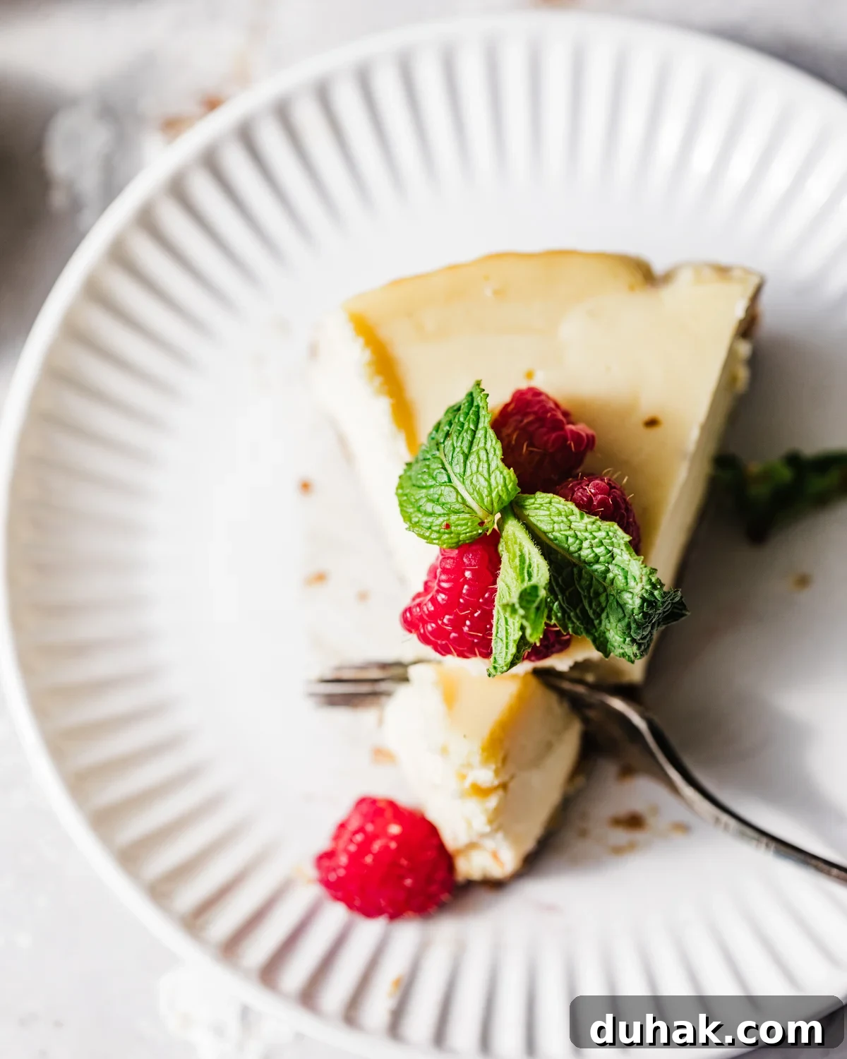 Silky Mascarpone Cheesecake Recipe with Luscious Cream Filling 3 overhead photo of mascarpone cheesecake on a plate with a fork cutting a piece out of the slice.