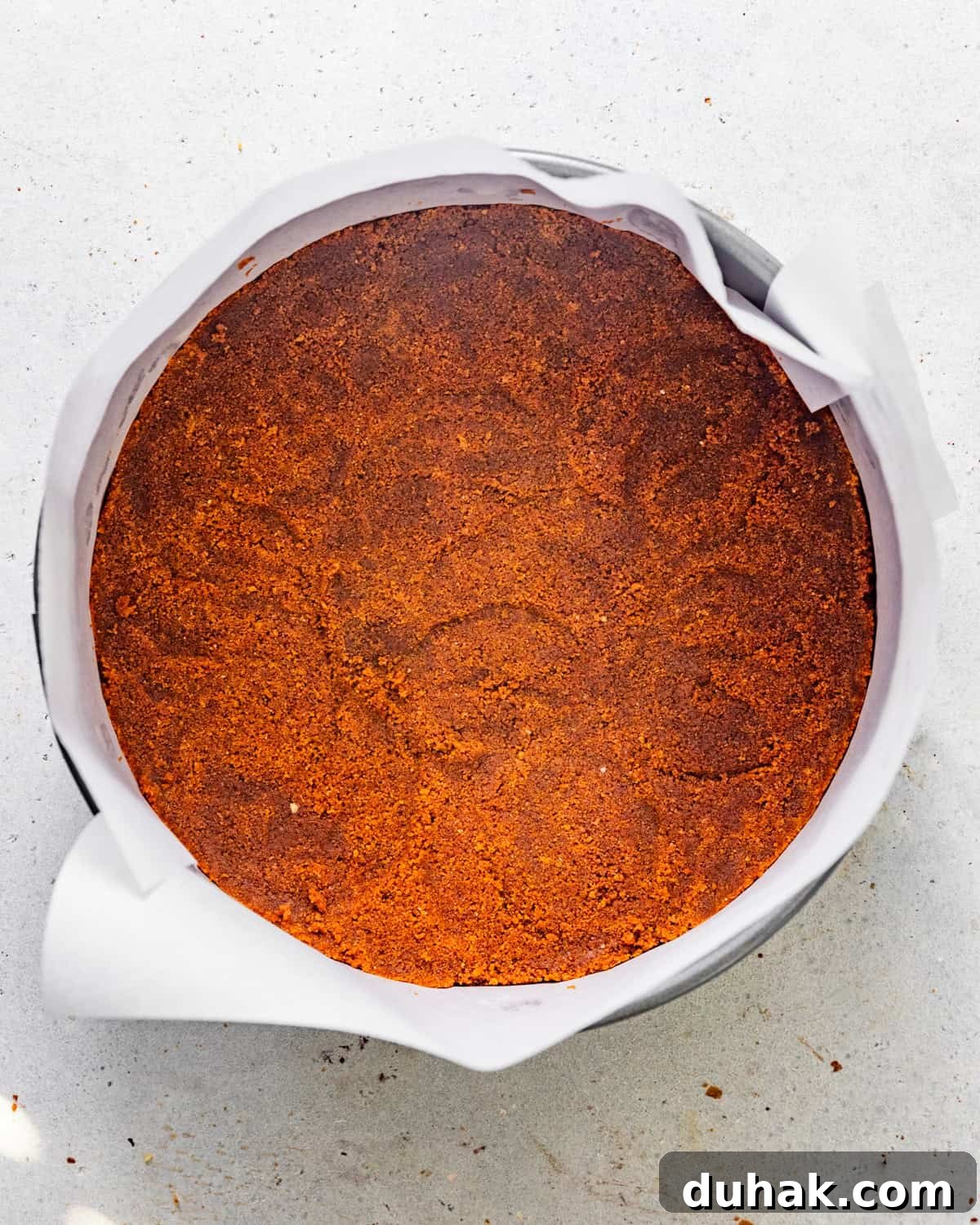 Silky Mascarpone Cheesecake Recipe with Luscious Cream Filling 5 biscoff cheesecake crust in a springform pan lined with parchment paper.