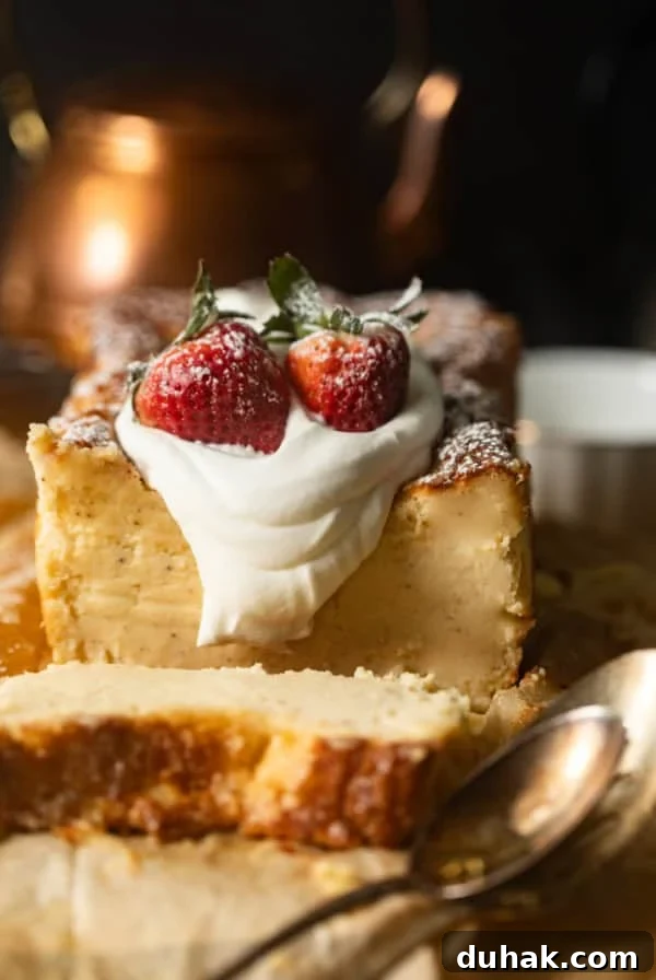 Silky Mascarpone Cheesecake Recipe with Luscious Cream Filling 9 loaf pan basque cheesecake on a piece of parchment paper topped with whipped cream and strawberries.