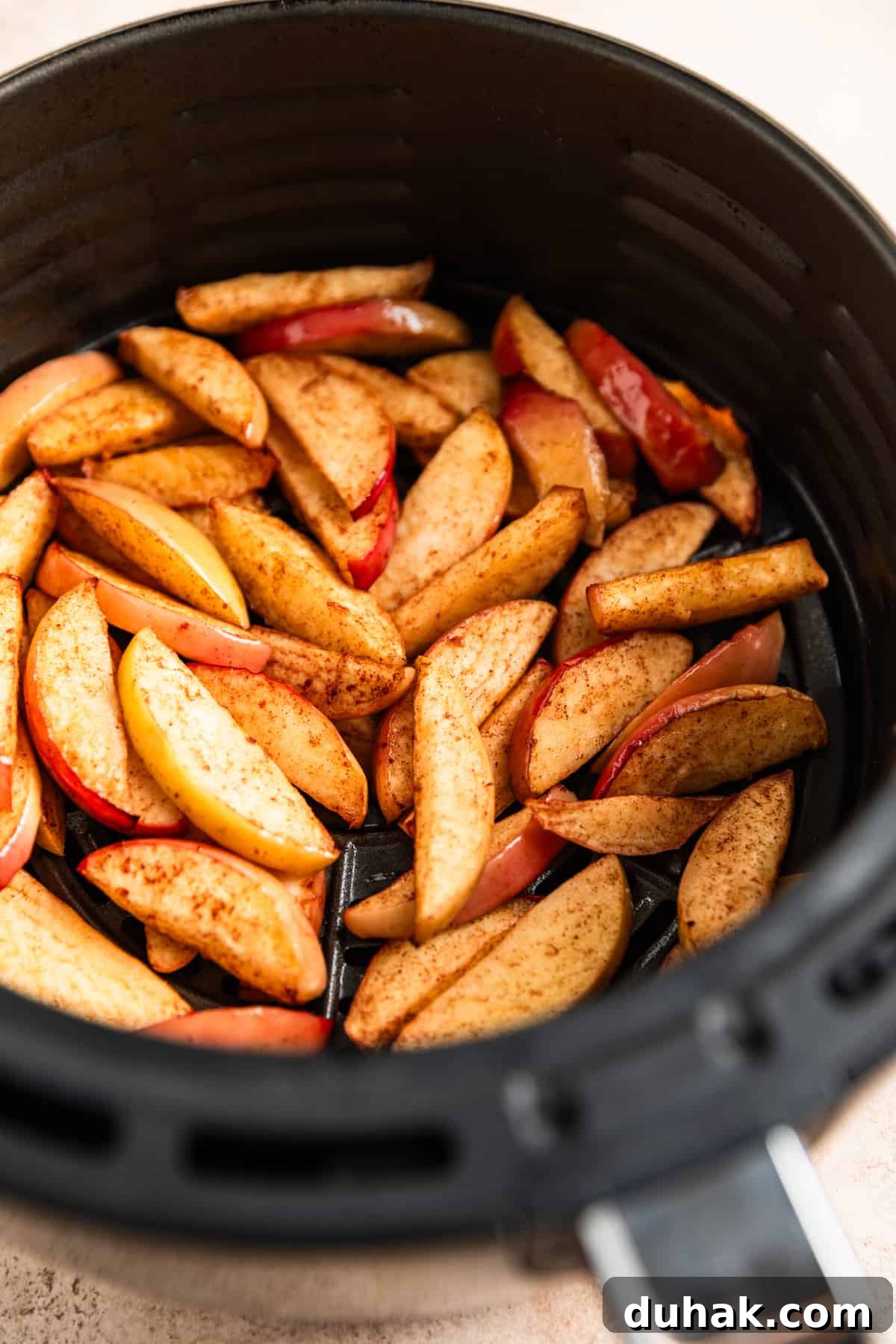 Cooked apple slices in air fryer basket.