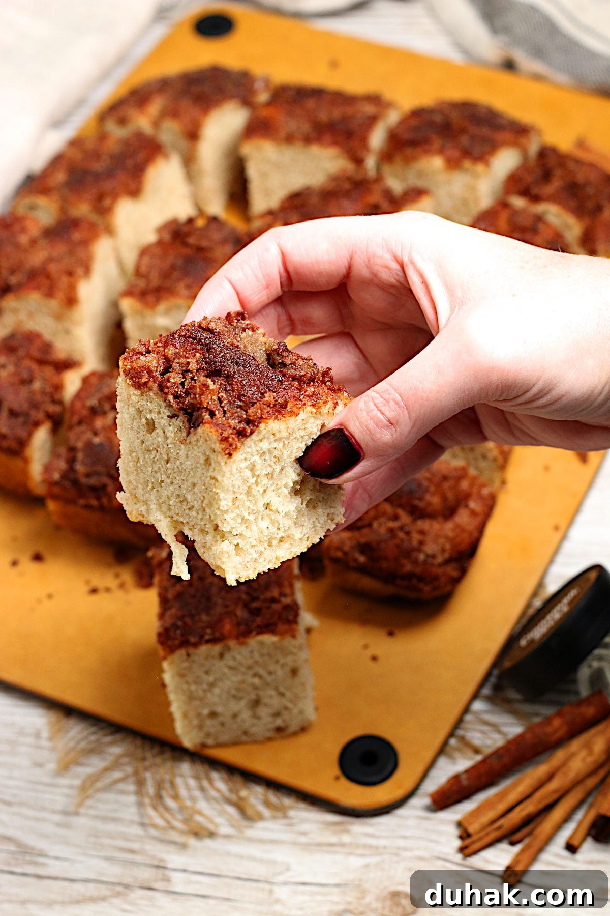 Cinnamon Toast Focaccia Recipe: Crispy Sweet Breakfast Bread 5 A hand holding a piece of Cinnamon Toast Focaccia.