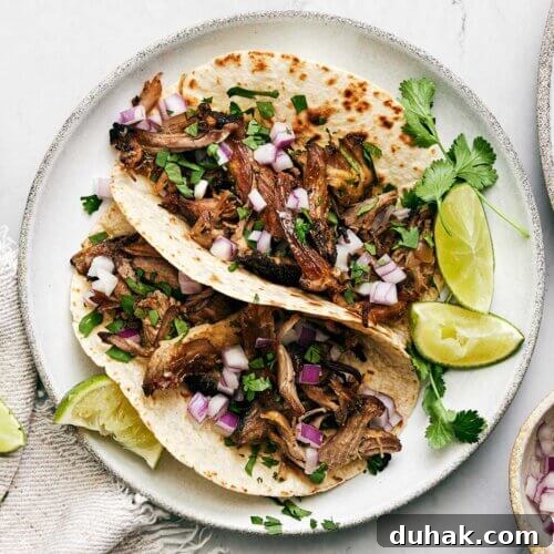 A plate of carnitas tacos with limes.