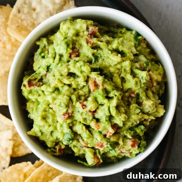 Guacamole recipe in a bowl next to tortilla chips.