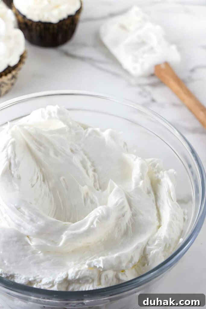 A bowl of cooked meringue buttercream in front of a spatula. 