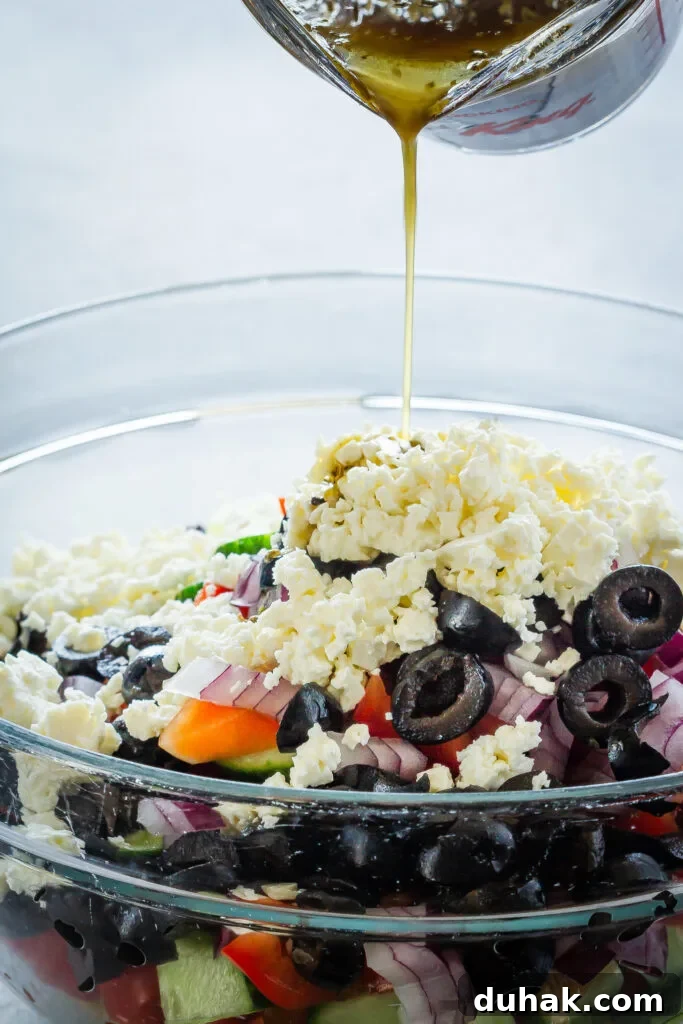 Greek-Style Quinoa Salad with Feta, Cucumber & Olives 5 dressing being poured onto Greek quinoa salad