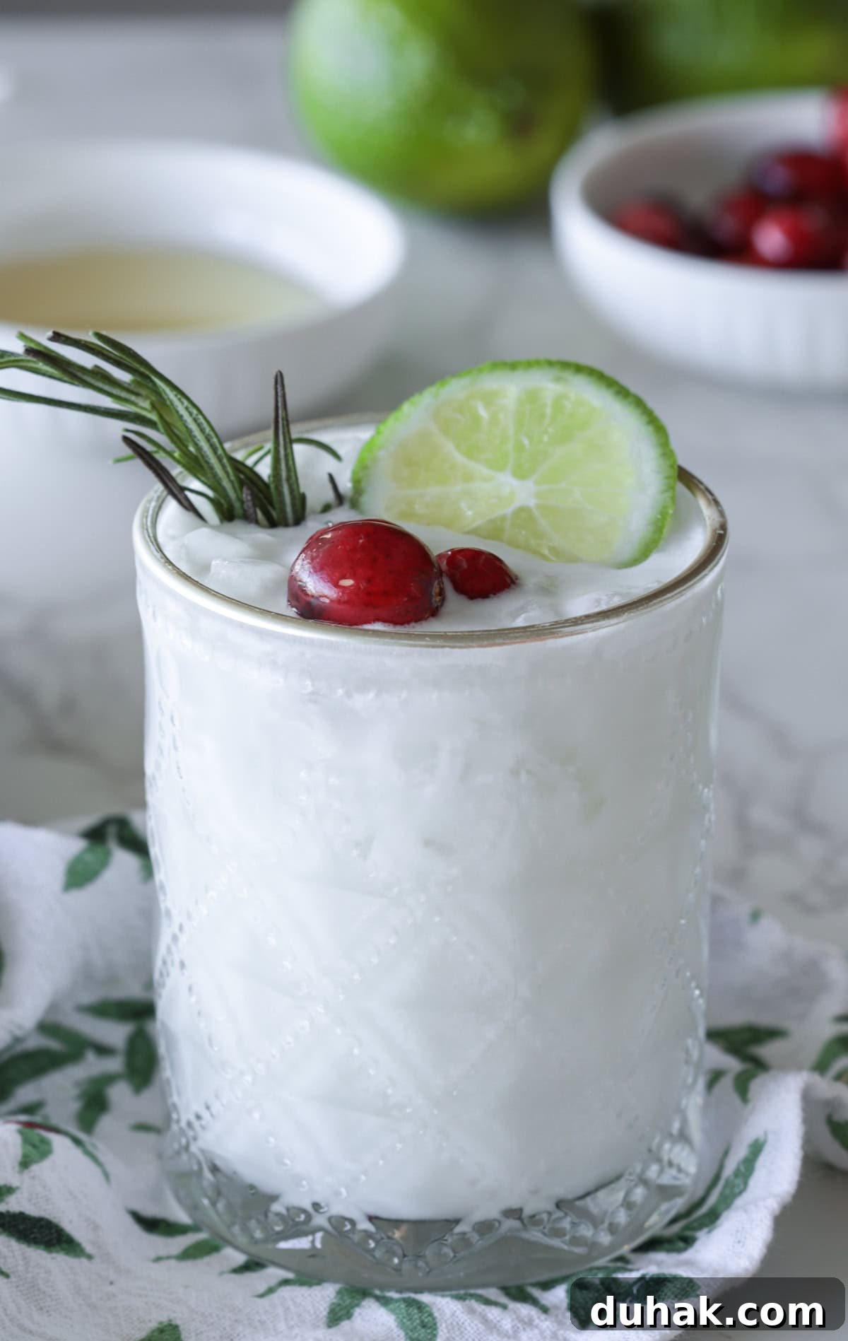 White margarita with lime and cranberry garnish.