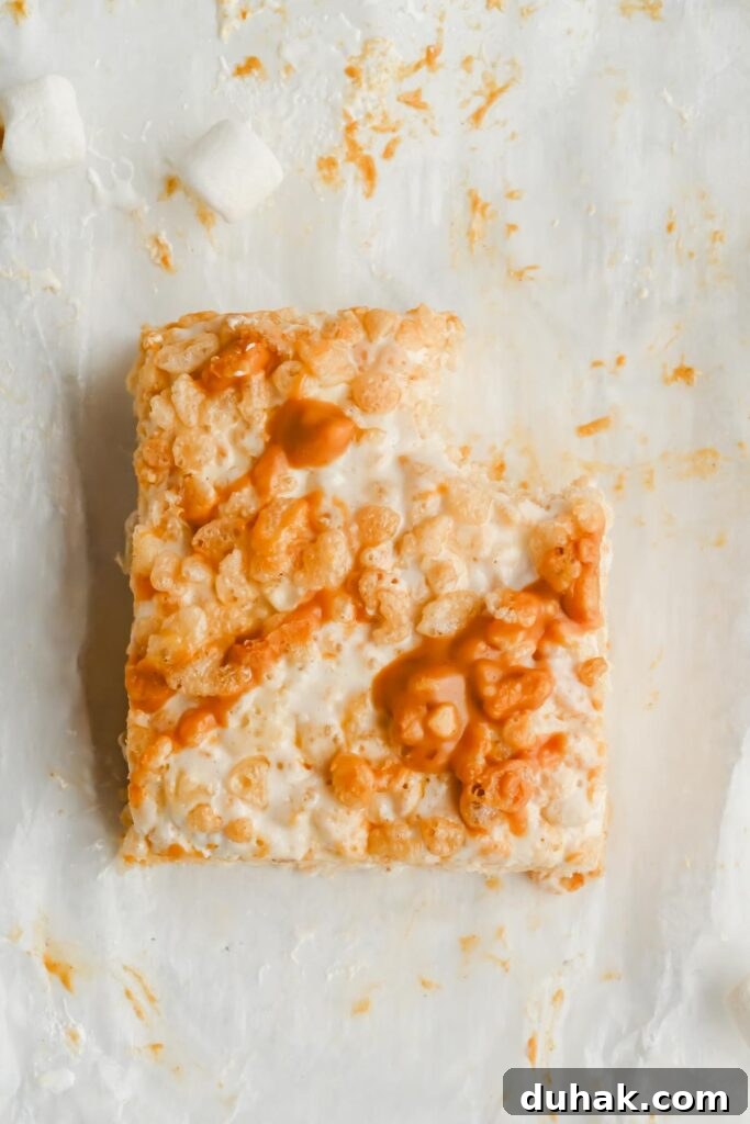 one marshmallow fluff rice krispie treat with bite taken out of it on white parchment.