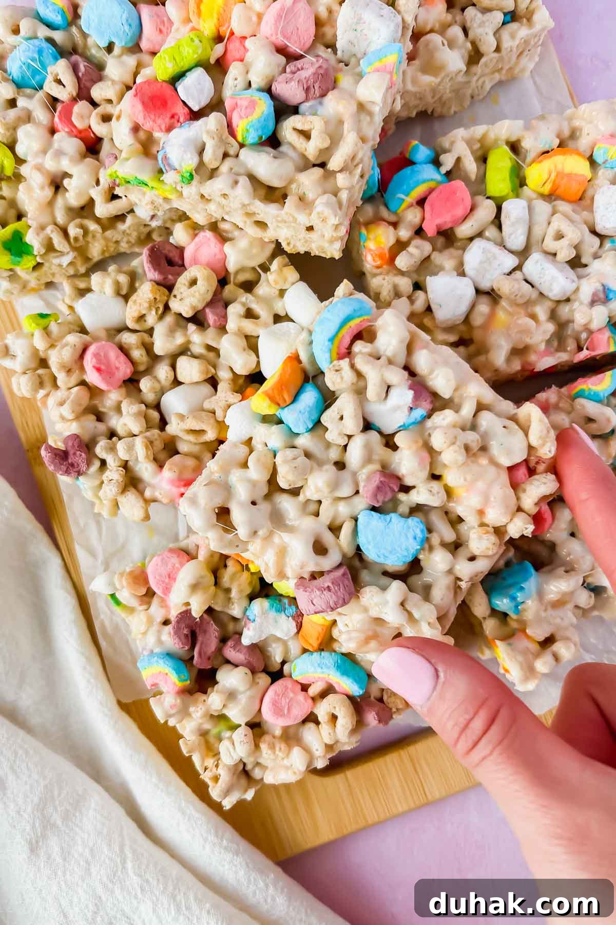 lucky charm rice krispie treats cut into squares with hand picking one up.