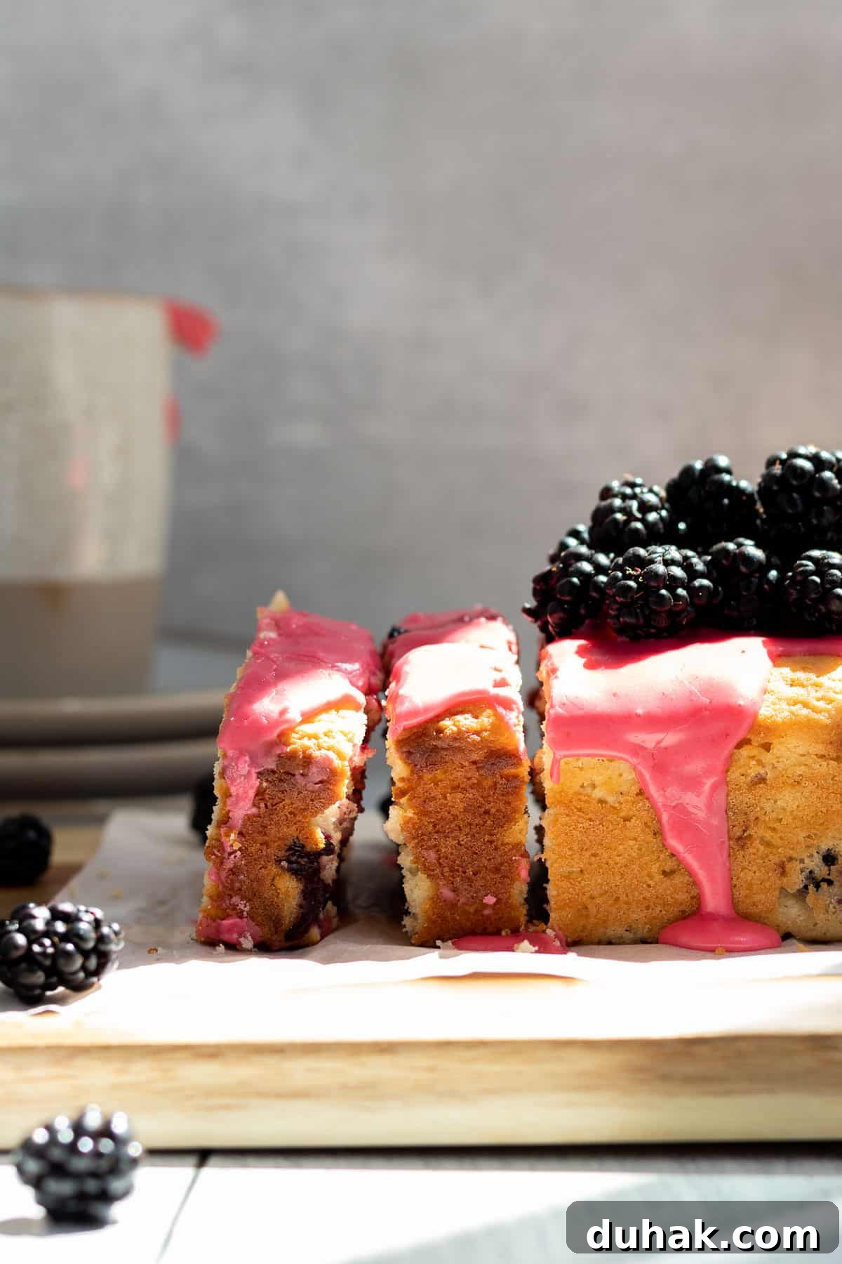 Lemon Blackberry Quick Bread Recipe for Moist Loaves 2 Blackberry lemon bread on a wood cutting board, with 2 slices cut and blackberries piled on top
