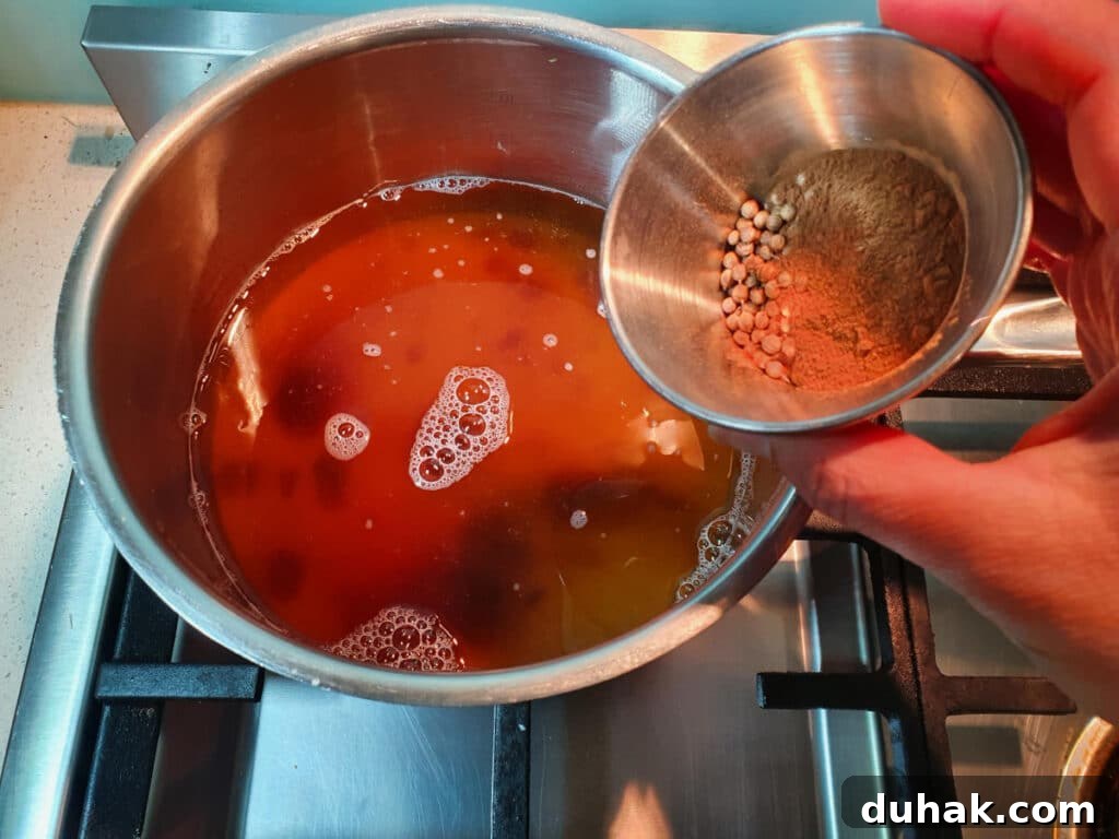 How to Make Homemade Cola Soda from Scratch 11 adding small bowl of measured spices to saucepan.