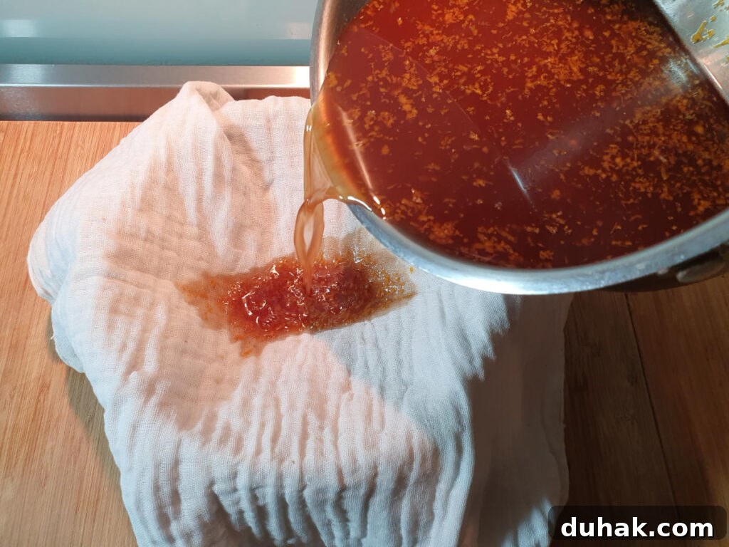 How to Make Homemade Cola Soda from Scratch 15 straining cola through a cheesecloth lined sieve over a bowl.