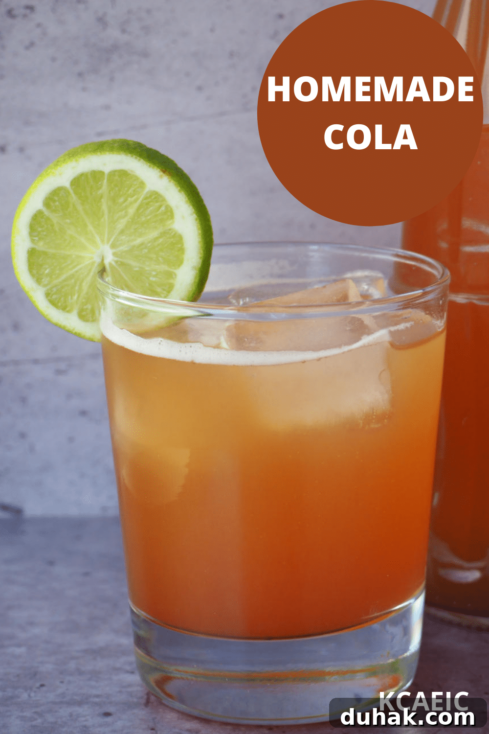 How to Make Homemade Cola Soda from Scratch 21 Glass of homemade cola with ice, lime circle garnish and bottle of cola beside it and text overlay, homemade cola, KCAEIC.