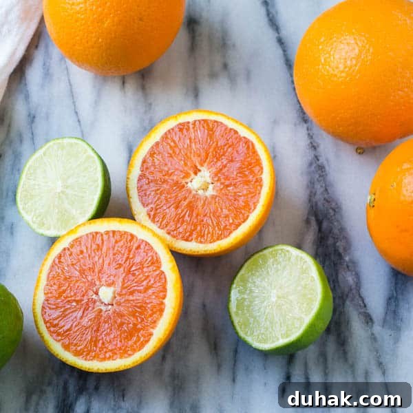 Sparkling Cara Cara Orange Margaritas — Festive Citrus Cocktail Recipe 2 sliced cara cara oranges and limes on a marble background