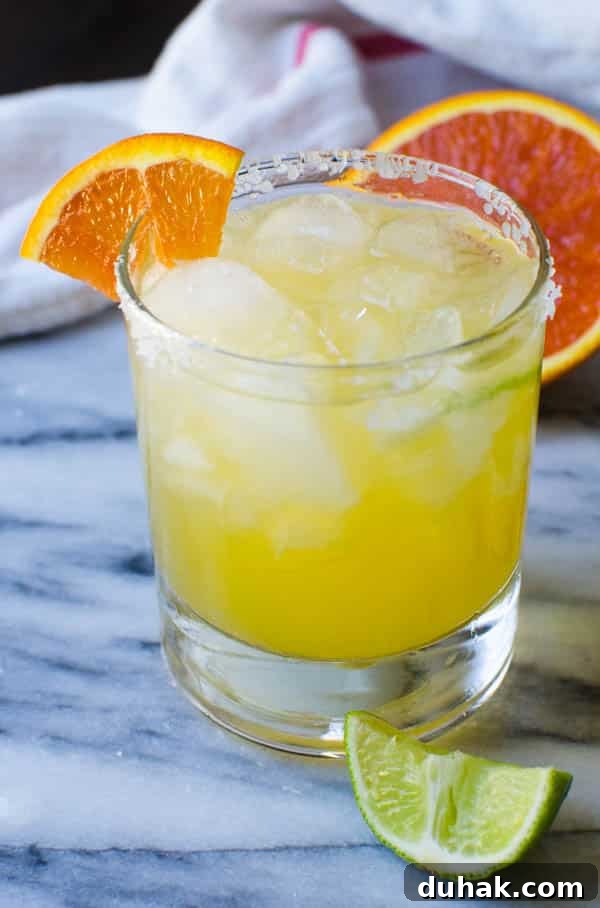 Sparkling Cara Cara Orange Margaritas — Festive Citrus Cocktail Recipe 11 A glass of Sparkling Cara Cara Margaritas with a lime wedge.
