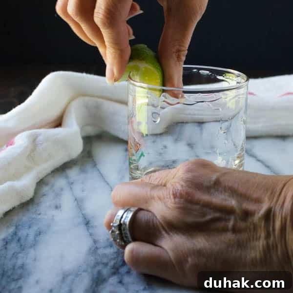 photo of a hand holding a lime and rimming a glass with the lime juice.