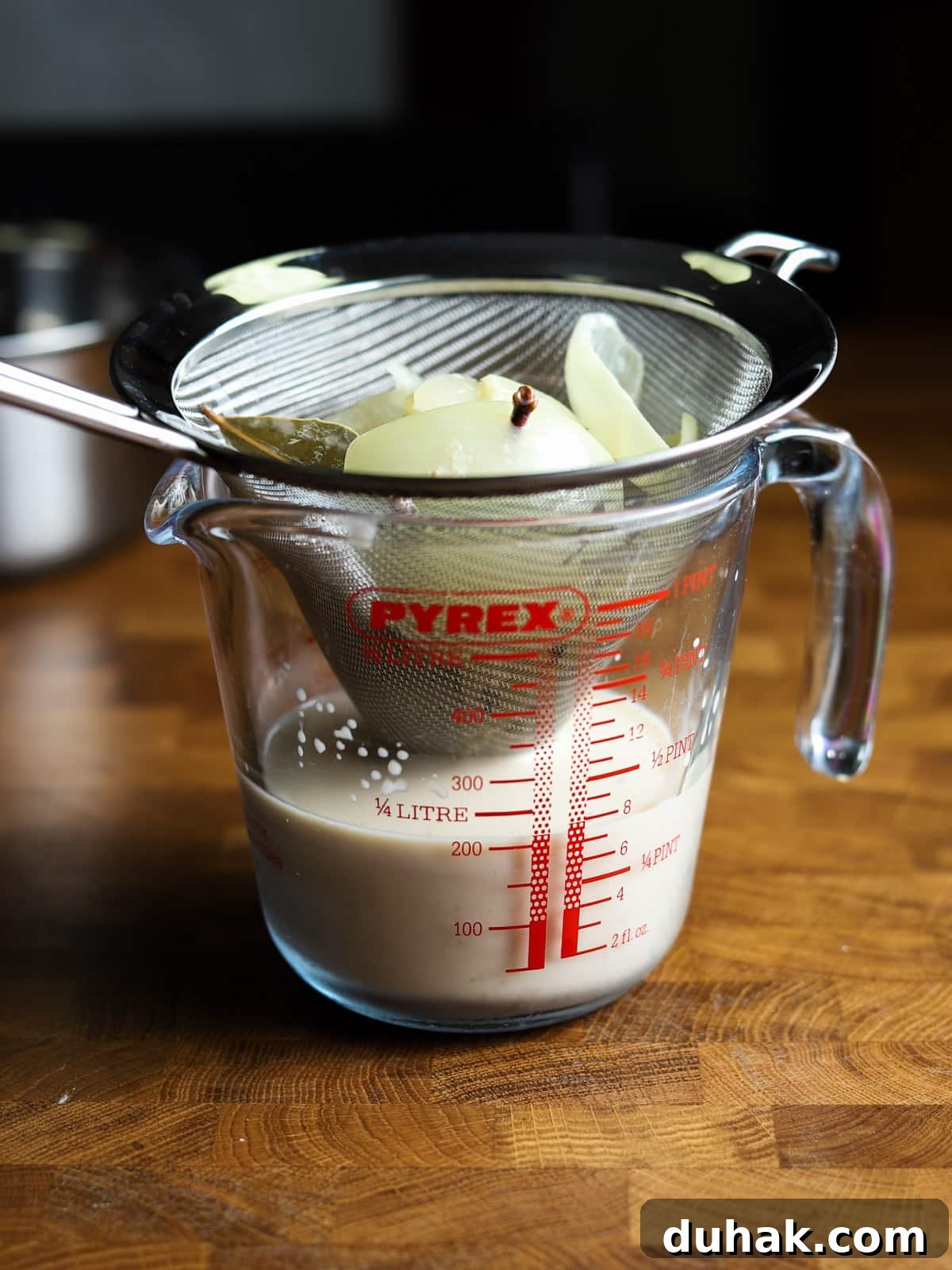 Photo of straining the milk through a sieve over a jug.