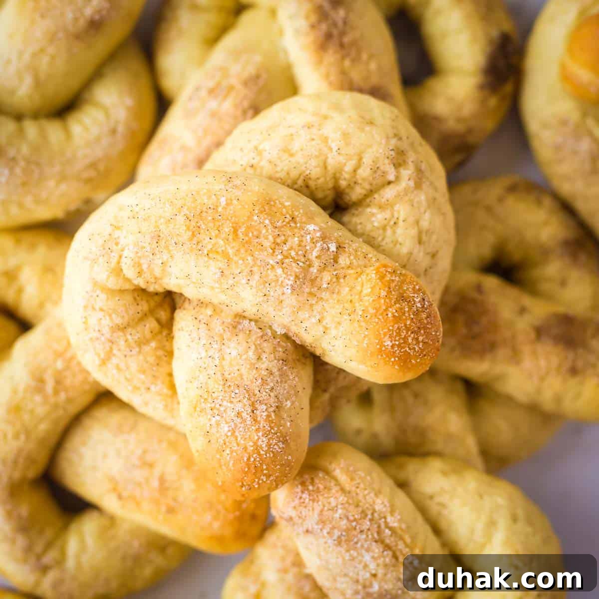 Overhead shot of multiple soft pretzels stacked on each other with a close up of the cinnamon sugar on the top one.