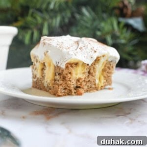 Creamy Eggnog Poke Cake Recipe for Holiday Dessert 14 piece of eggnog poke cake on a plate in front of greenery and a baking pan.