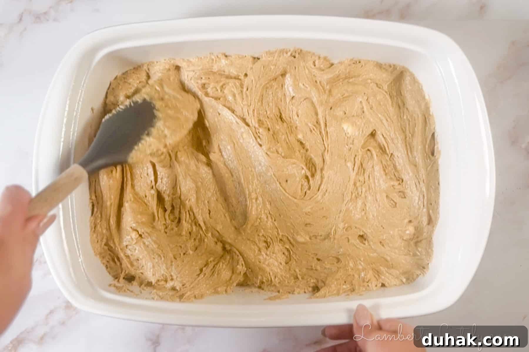 Creamy Eggnog Poke Cake Recipe for Holiday Dessert 4 spreading spice cake batter in a baking dish.