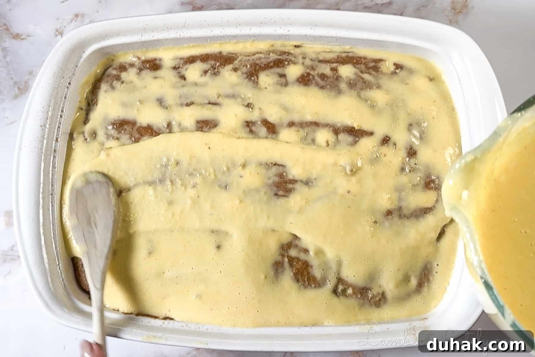 Creamy Eggnog Poke Cake Recipe for Holiday Dessert 6 pouring eggnog pudding mixture over the cake with holes.