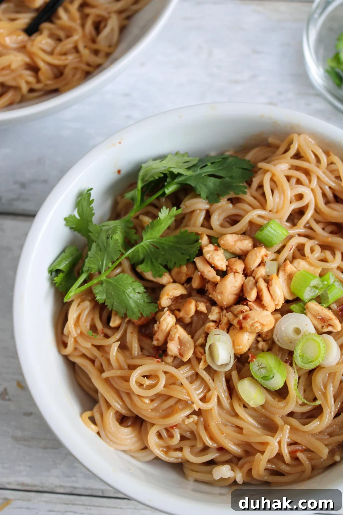 Bowl of spicy thai peanut butter ramen with garnishes. 
